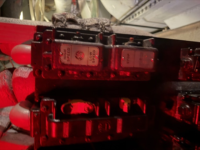 A General Electric motor controller with HIGH SPEED, LOW SPEED, and STOP push-button stations sits amid red-painted lagged piping in a machinery space aboard USS Alabama.