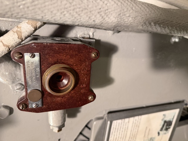 A bulkhead-mounted phenolic electrical connector aboard USS Drum bears a metal plate reading "BAT. TES. SYS. CONTROL RM. XJ06," with a white fabric-lagged pipe running along the bulkhead to its right.