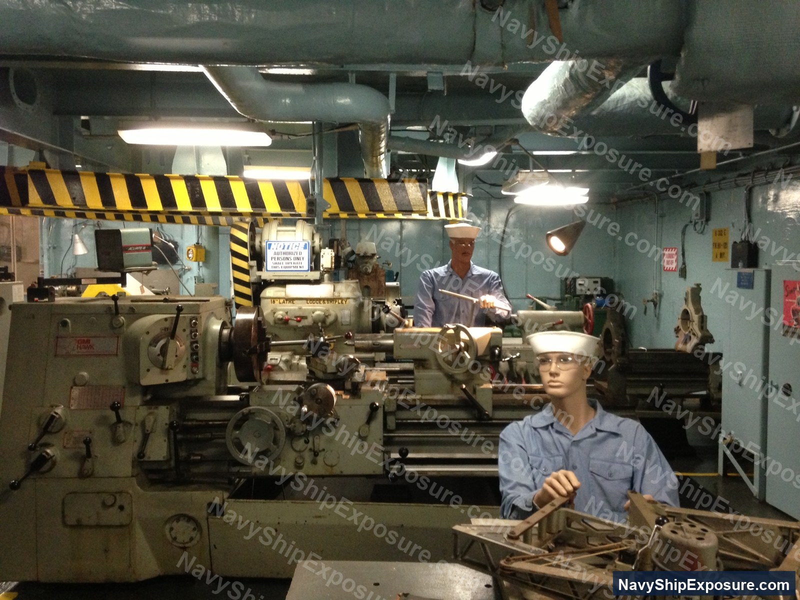 Interior of naval machine shop with sailors operating equipment
