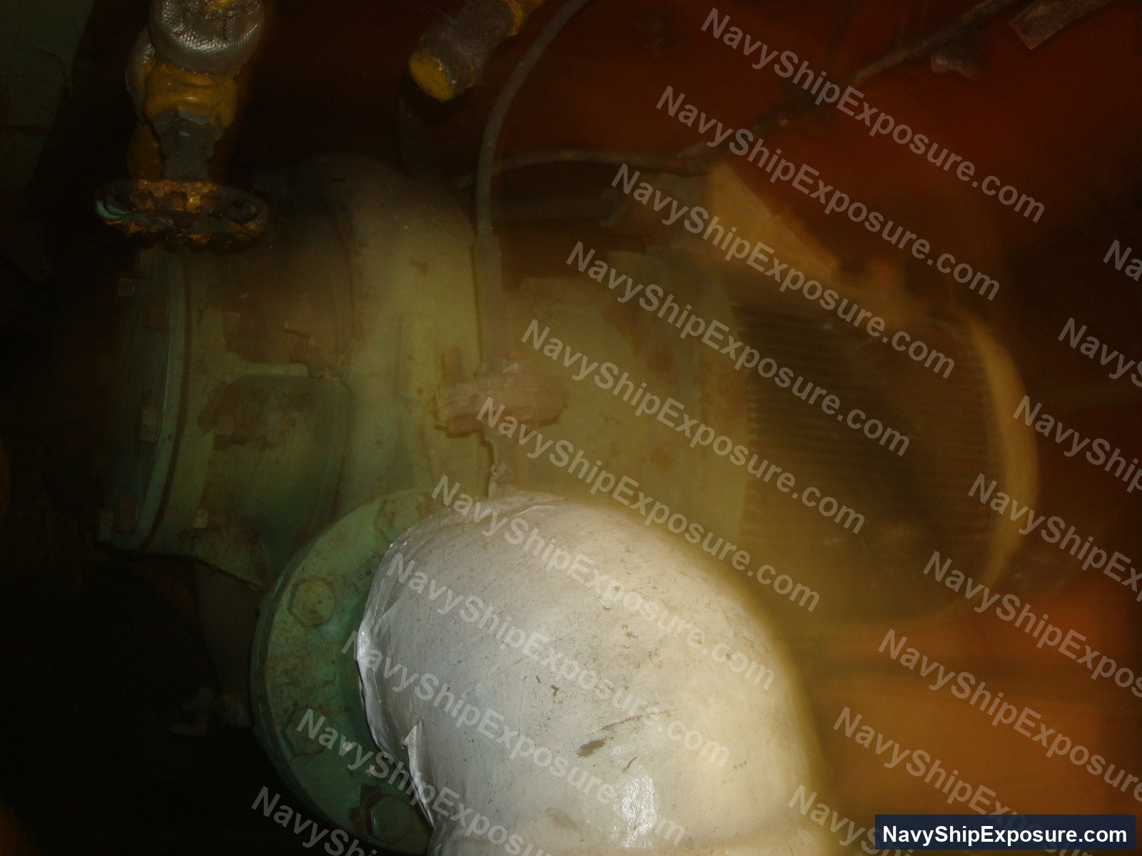 USS Midway — Engine room or machinery space piping with white insulation material (likely asbestos-containing) wrapped around a large cylindrical component, showing typical shipboard equipment configuration from the USS Midway era.