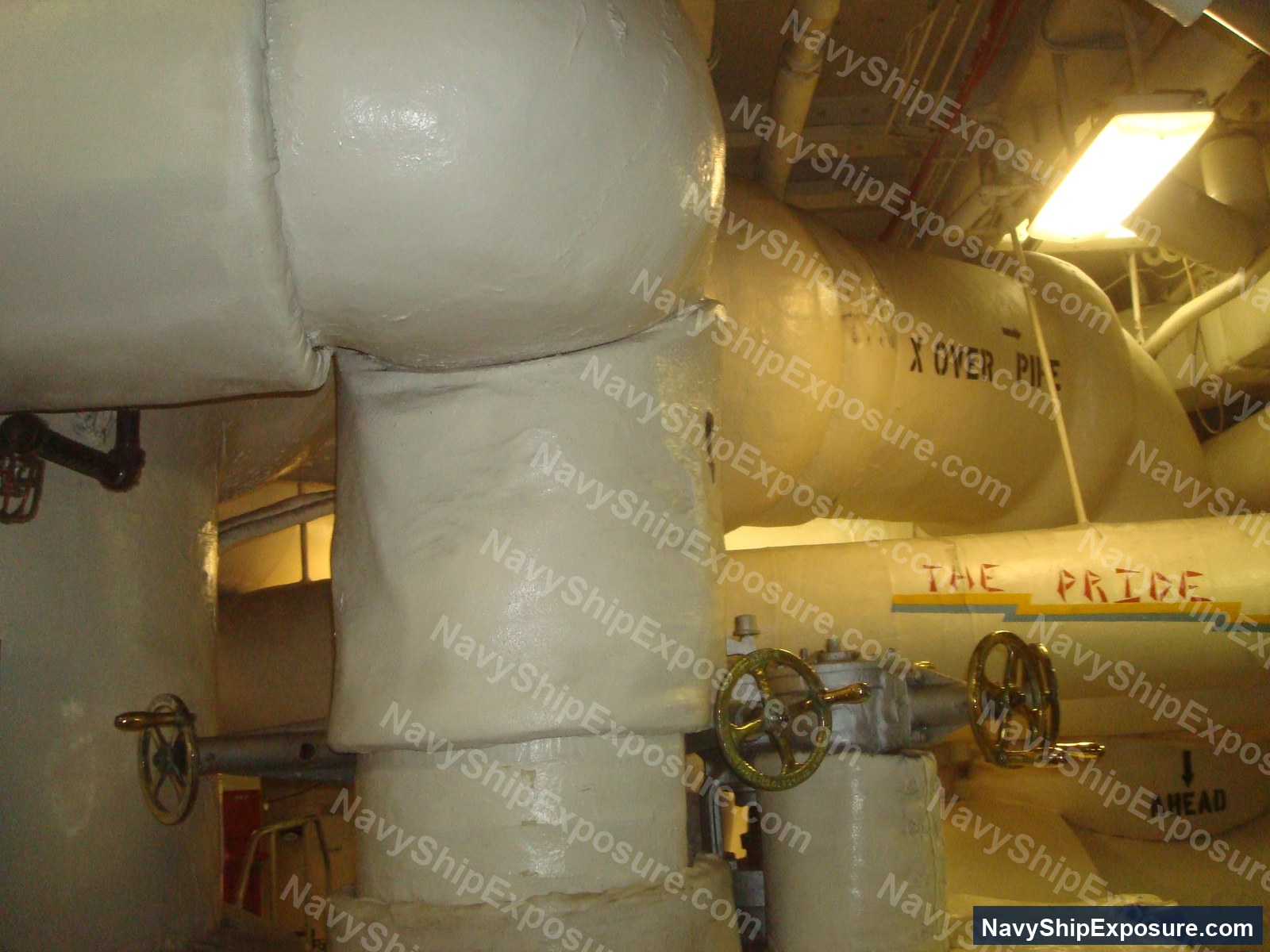 USS Midway — Engine room or machinery space aboard USS Midway showing large cylindrical equipment with hand wheels, piping, insulation wrapping, and industrial naval machinery typical of a 1940s-era aircraft carrier's propulsion systems.