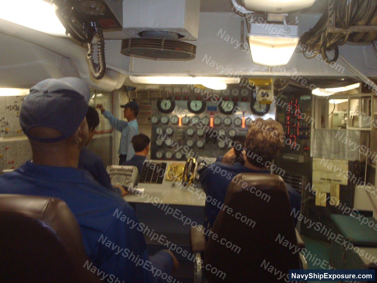 USS Midway — Interior view of USS Midway engine room showing control panels, gauges, monitoring equipment, and naval personnel operating machinery spaces typical of 1940s-era aircraft carrier propulsion systems.