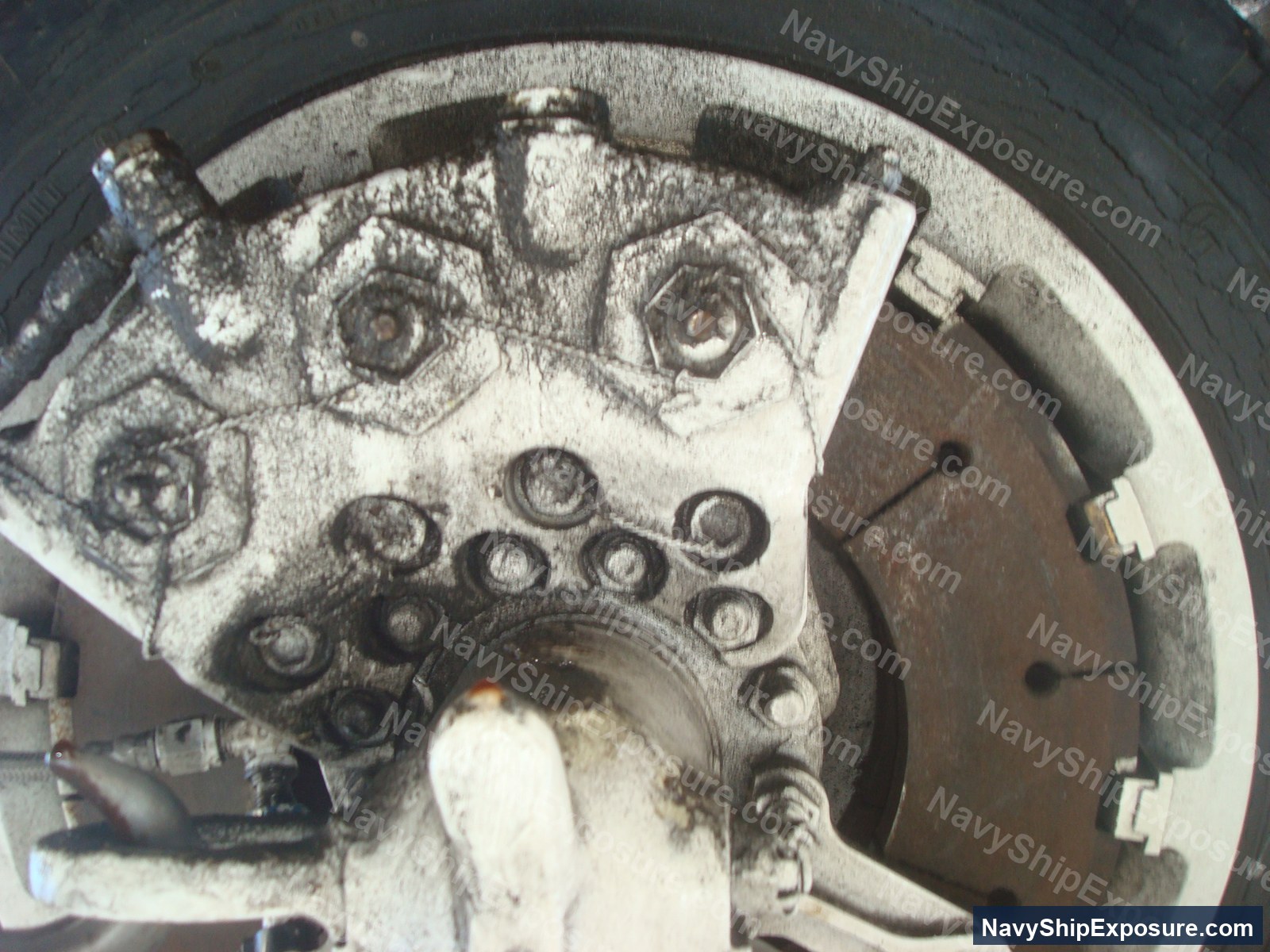 USS Midway — Close-up photograph of ship machinery or engine components showing gears, bolts, and metal fittings characteristic of naval propulsion or auxiliary equipment from the USS Midway era.