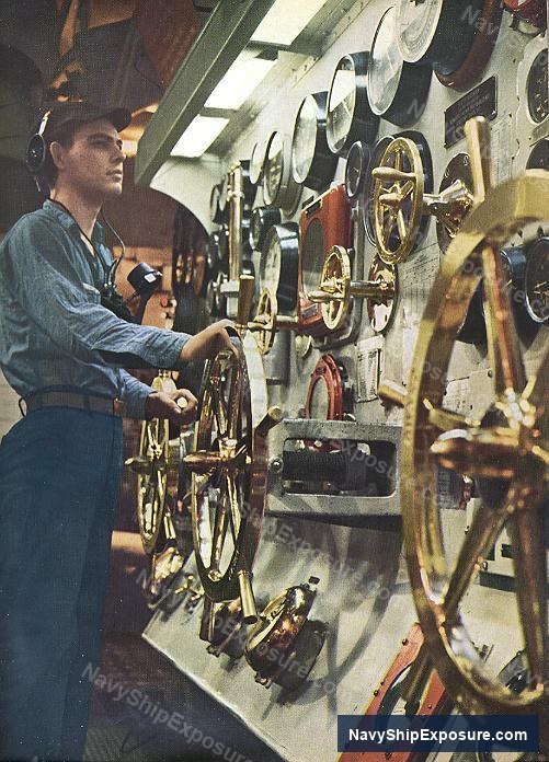 USS Midway — A worker operates machinery in an engine room or machinery space aboard USS Midway, with multiple brass fittings and mechanical components visible along the wall.