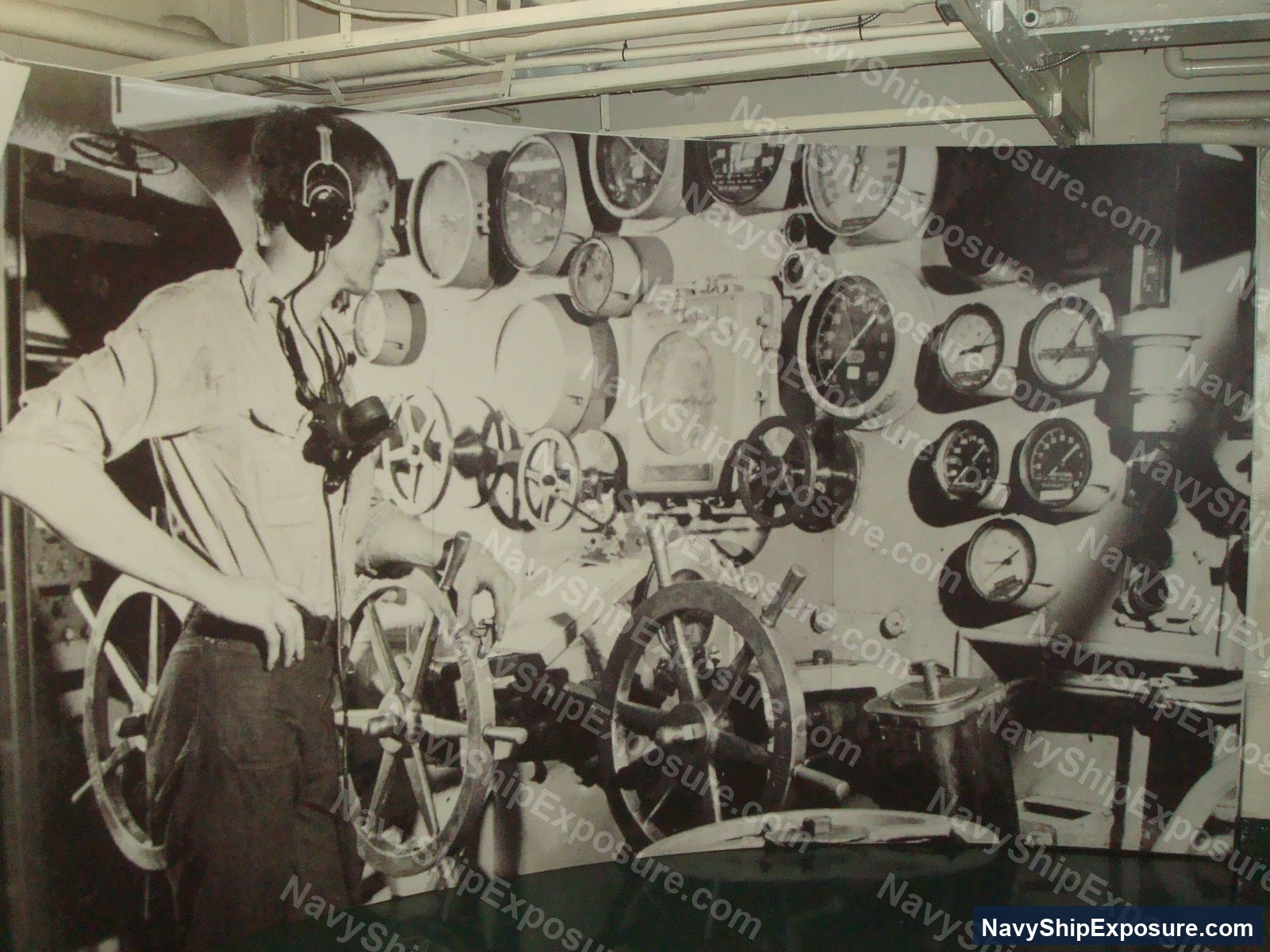 USS Midway — A sailor operates at the ship's wheel in the engine room of USS Midway (CV-41), with numerous analog gauges and mechanical controls visible on the surrounding bulkhead.