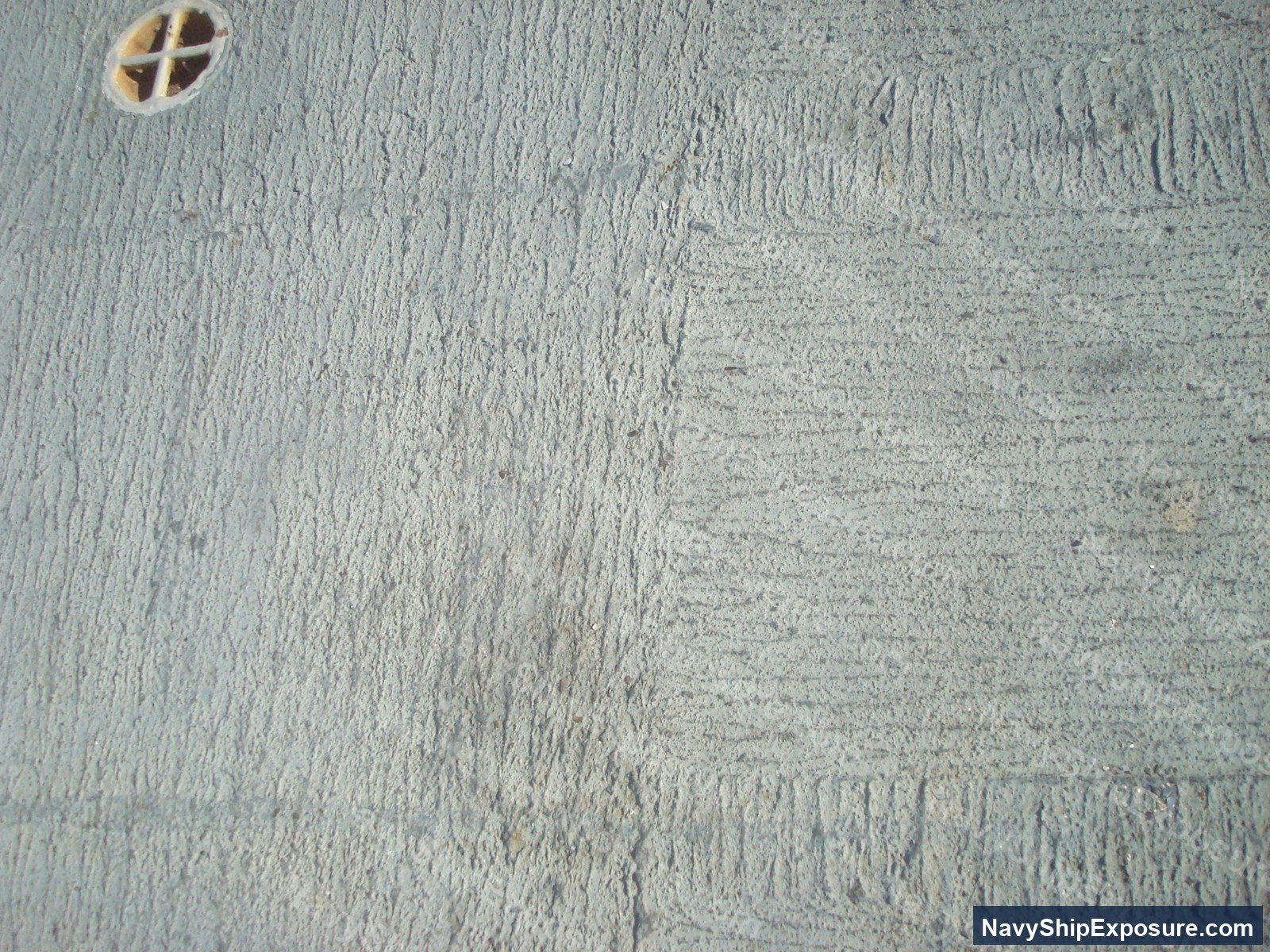 USS Midway — Interior surface of a ship machinery or engineering space showing textured insulation material with visible wear patterns and a circular ventilation or access port with a cross-pattern grate.
