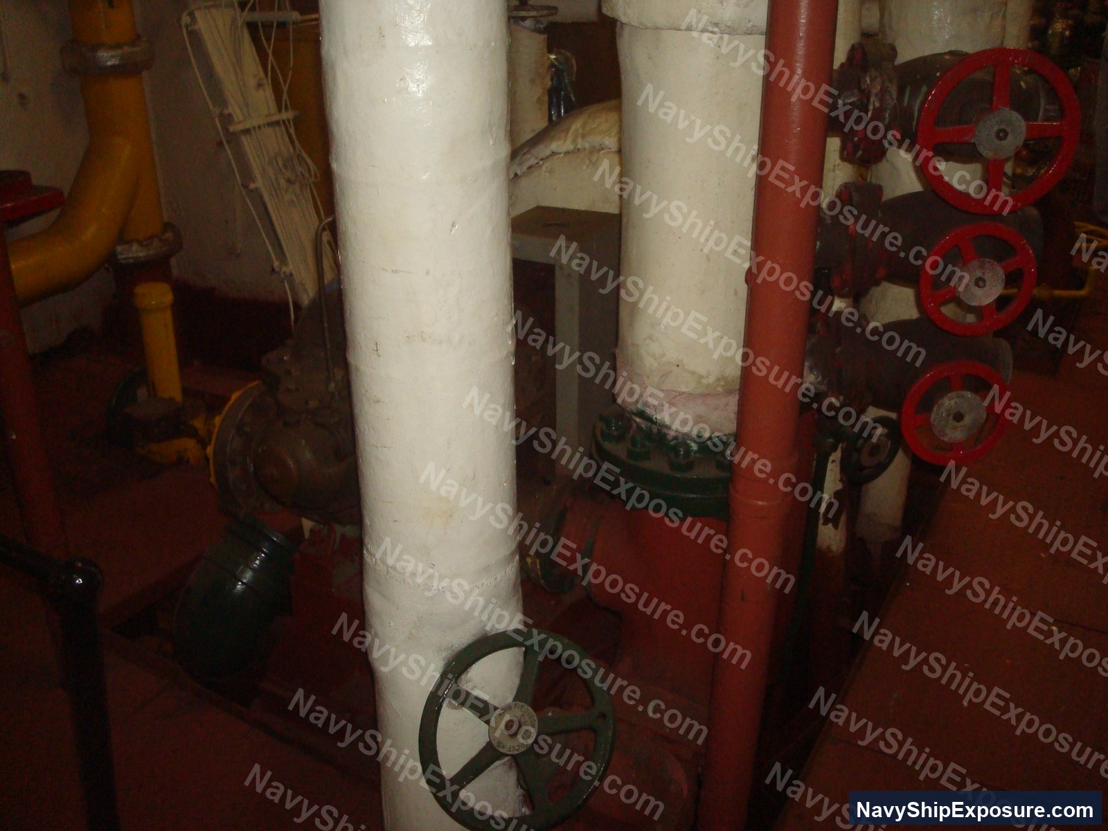 USS Midway — Engine room or machinery space aboard USS Midway showing large cylindrical pipes with manual valve wheels, typical of steam propulsion system components from the 1945-1992 era vessel.